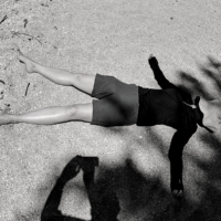 woman lying down in the sand with hat on her face